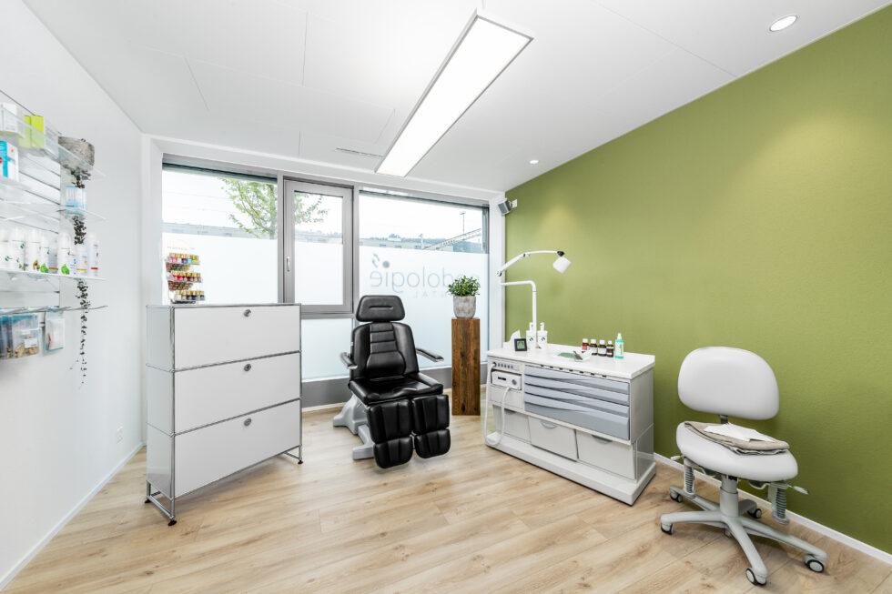 Das Behandlungszimmer der Podologie Rontal mit einer grünen Wand und weissen Möbeln.